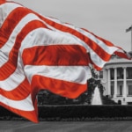 Black and white photo of the US White House with color splash of an American flag