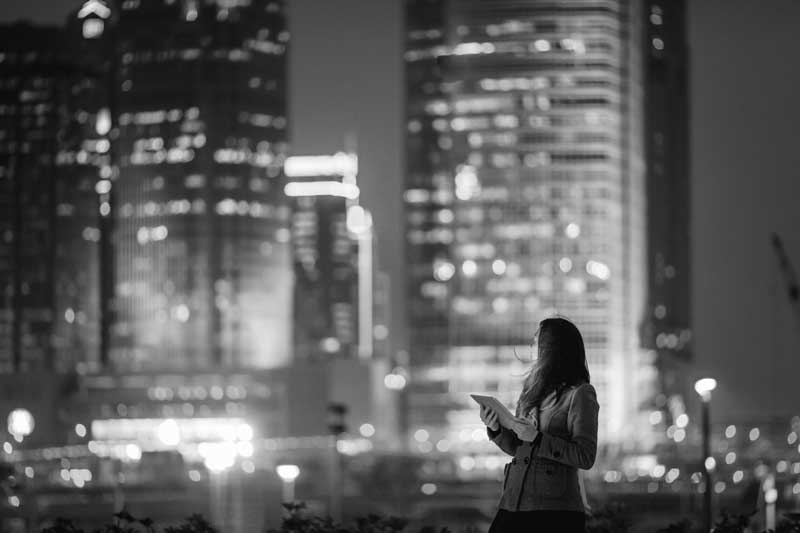 Mujer sosteniendo una tableta, mirando el horizonte