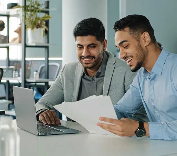 Two Suryoday Small Finance Bank colleagues reviewing documents at a laptop